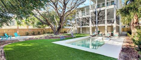 A two-story house with a swimming pool, a well-maintained lawn, and outdoor seating.