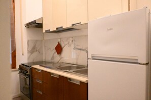 A kitchen with a stove, oven, sink, and a white refrigerator.