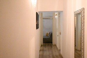 A narrow hallway with a door on the right, a mirror on the wall, and a glimpse of a room with a bed and a window. - A42 - Ancona, two-room apartment in the center (Ancona)