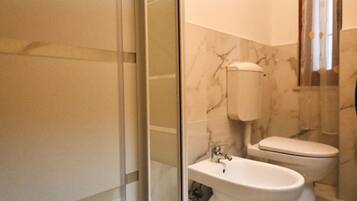 A bathroom with a glass shower enclosure, a sink, and a toilet.