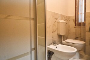 A bathroom with a glass shower enclosure, a sink, and a toilet.