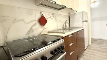 Una cucina con fornelli, forno e frigorifero.