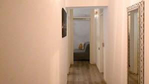 A narrow hallway with a door on the right, a mirror on the wall, and a glimpse of a room with a bed and a window. - A42 - Ancona, two-room apartment in the center (Ancona)