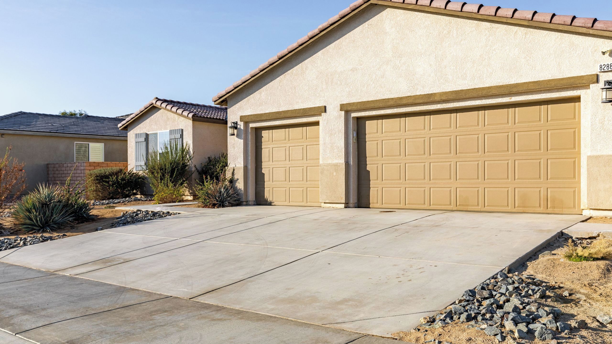 A residential house with a garage, a driveway, and landscaping.
