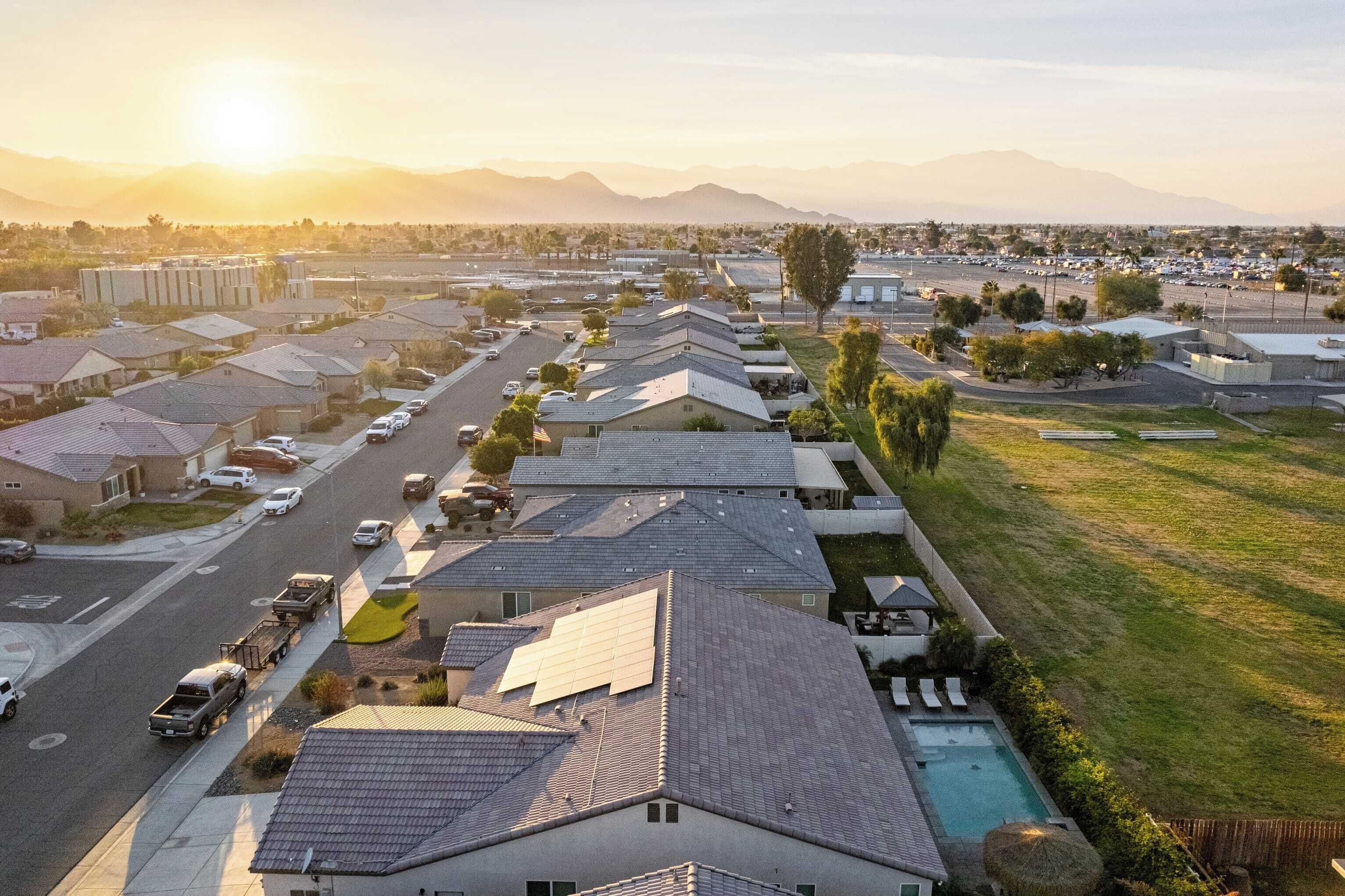A residential area with houses, a road, and a mountain range in the background.