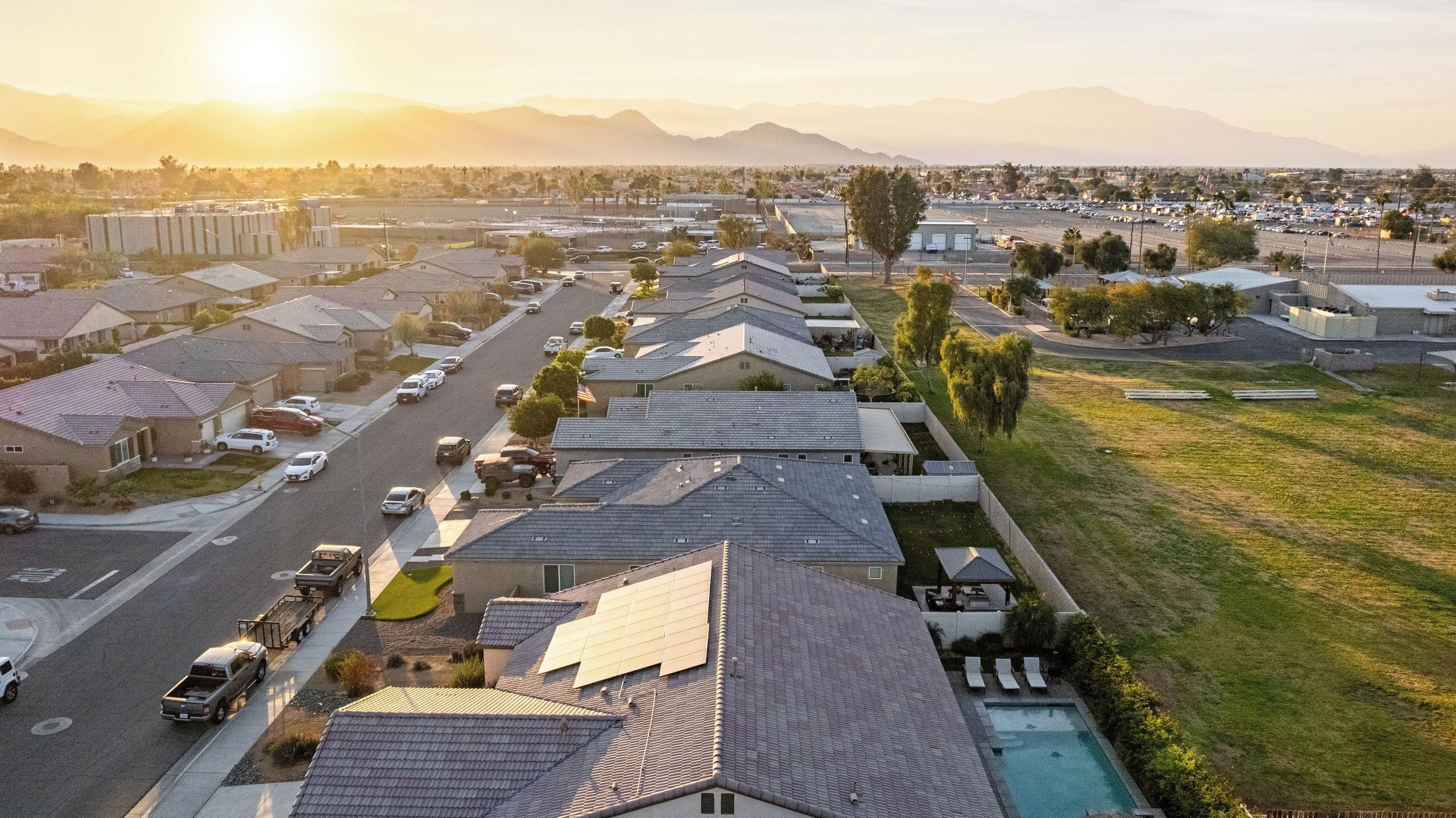 Un quartier résidentiel avec des maisons, une route et, au loin, une chaîne de montagnes.