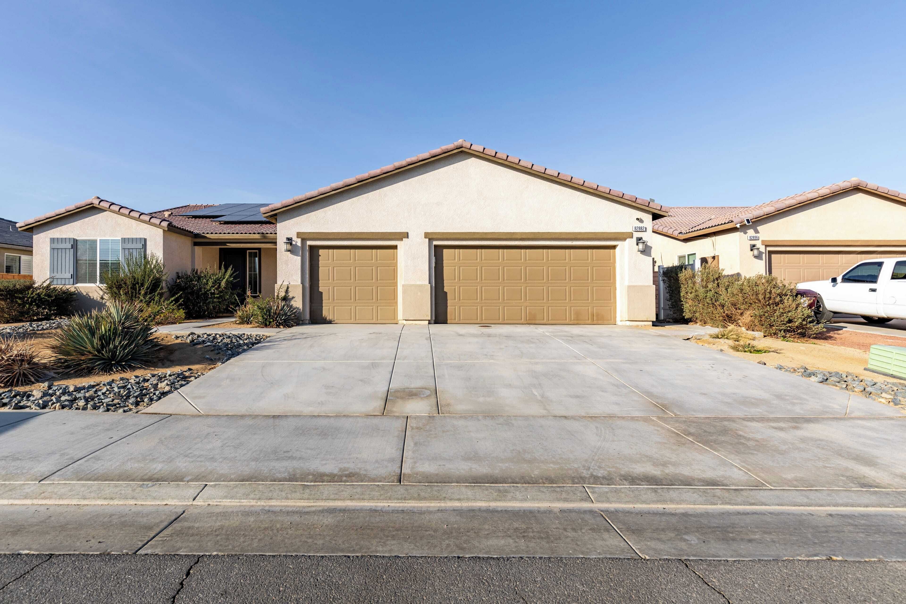 A residential house with a driveway, garage, and a white car parked in the driveway.