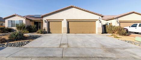 A residential house with a driveway, garage, and a white car parked in the driveway.