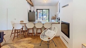 A modern kitchen with a dining area, wooden flooring, and a large window.