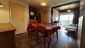 Un comedor con mesa y sillas de madera, una cocina con microondas y un balcón con vistas.