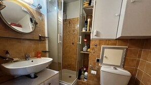 Un baño compacto con lavamanos blanco, inodoro y cabina de ducha.