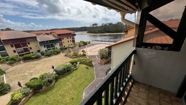 Un balcón con vistas a un patio, edificios y una masa de agua.