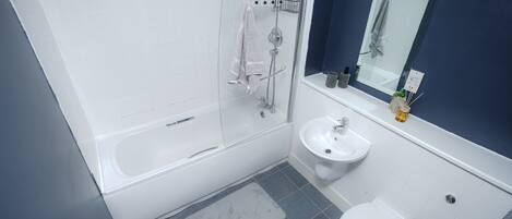 A modern bathroom with a glass-enclosed shower, a white sink, and a toilet.