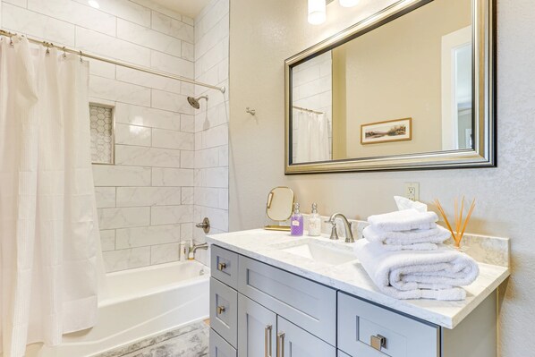 Un baño moderno con bañera, tocador con espejo y zona de ducha.