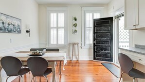 Una cocina luminosa y amplia con suelo de madera, armarios blancos y ventanas grandes.