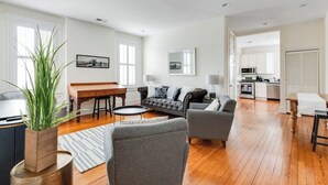 Un salón amplio con sofá, sillones, una mesa de comedor y una zona de cocina.