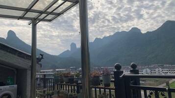 Un balcón con plantas en macetas y vistas a las montañas.