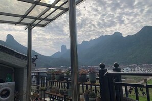 A balcony with potted plants and a view of mountains. - Old Village Chief Hostel (Xianju)