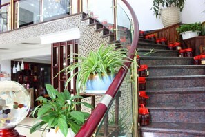 A staircase with red steps, a potted plant, and a glass railing. - Old Village Chief Hostel (Xianju)