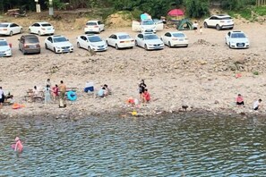 Una playa arenosa con coches estacionados y gente realizando diversas actividades cerca del agua.