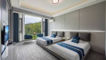 Habitación de hotel con dos camas, televisión, escritorio y balcón con vistas a zonas verdes.