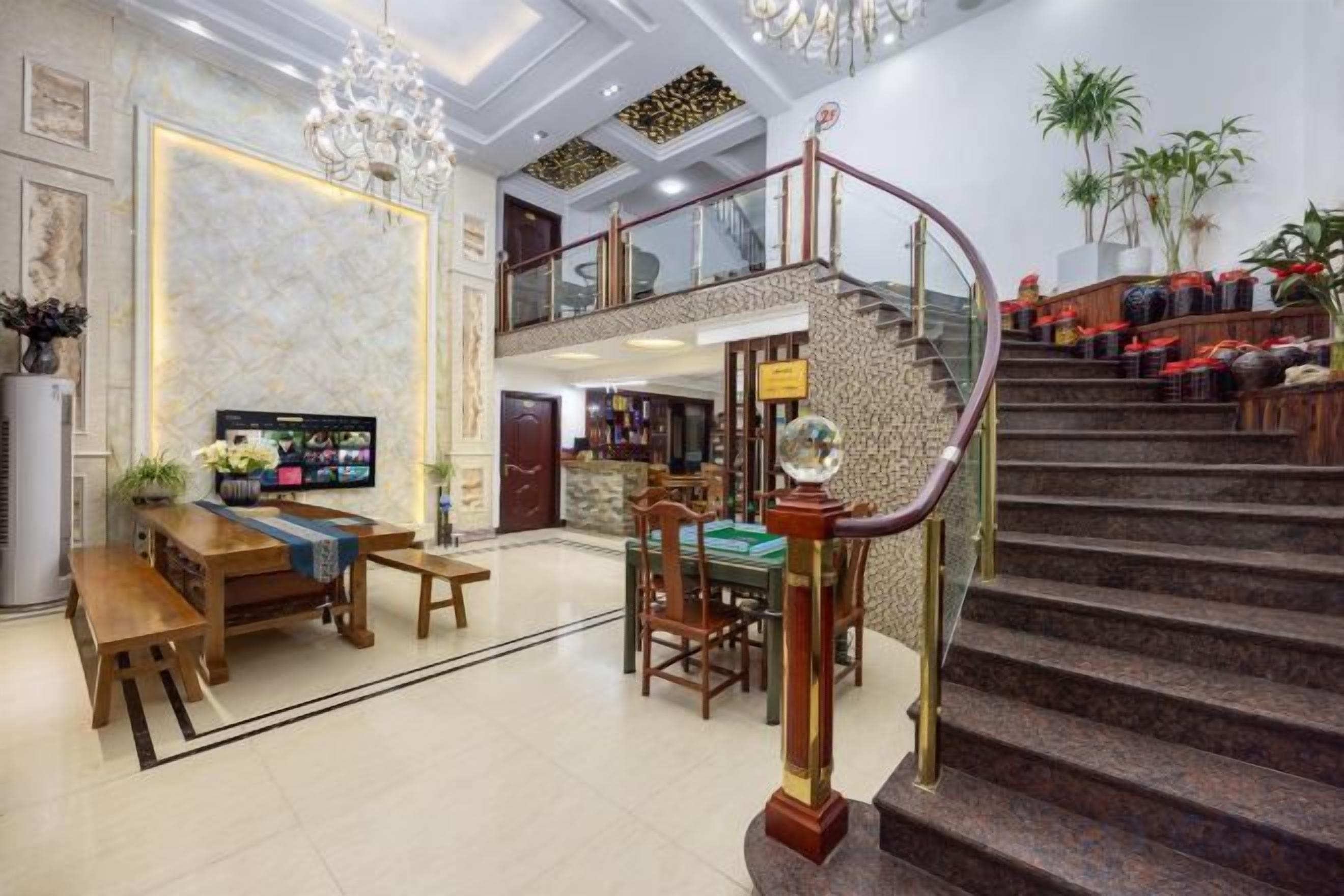 Un hall d’entrée spacieux avec un grand escalier, un coin salon avec une table basse et un téléviseur.