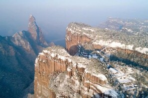 A mountainous landscape with a prominent rock formation and a small building. - Old Village Chief Hostel (Xianju)