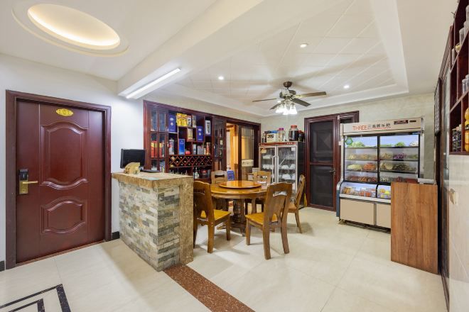 Un comedor con una mesa redonda y sillas, una pequeña zona de bar con estanterías y un refrigerador con vitrina.