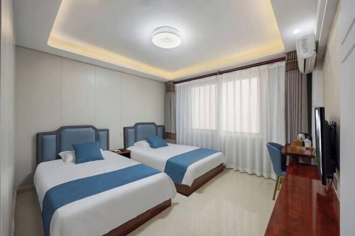 Habitación de hotel con dos camas, un escritorio, una silla y un televisor.