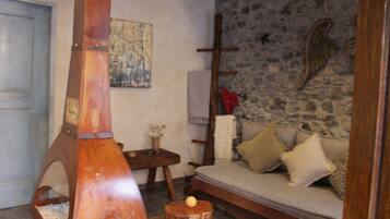 A rustic room with a stone wall, a wooden bench, and a sofa with cushions.