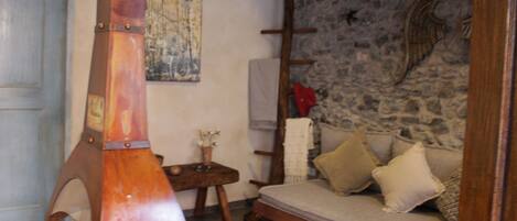 A rustic room with a stone wall, a wooden bench, and a sofa with cushions.