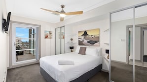 Une chambre à coucher avec un lit, un ventilateur de plafond, une fenêtre donnant sur un beau paysage et un tableau accroché au mur.