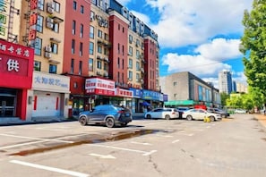 A street view with multiple commercial buildings, parked cars, and a clear sky. - Ease Hotel (Tonghua Eurasia Jiangnan Street Store) (Tonghua)