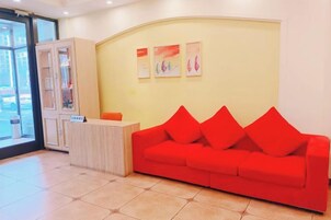 Zona de recepción con un sofá rojo, un mostrador y un armario.