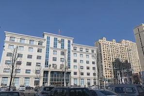 A multi-story building with a central entrance, surrounded by parked cars. - Ease Hotel (Tonghua Eurasia Jiangnan Street Store) (Tonghua)