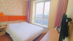 Een hotelkamer met een bed, een raam, een televisie en een muur met stippen.