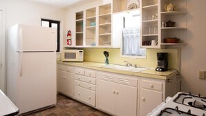 A compact kitchen with white cabinetry, a microwave, a sink, and a gas stove.