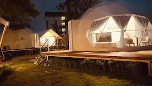 A series of dome-shaped tents with interior lighting, a wooden deck, and a grassy area. - Liting Hotel (Yulong)