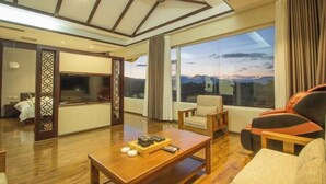 A modern hotel room with a large window, a wooden coffee table, a sofa, and a TV. - Liting Hotel (Yulong)