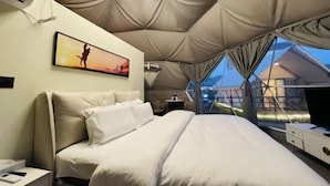 A tent-style room with a bed, a small table, and a chair. - Liting Hotel (Yulong)