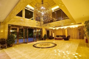 A spacious lobby with a high ceiling, a large chandelier, and a circular floor design. - Liting Hotel (Yulong)