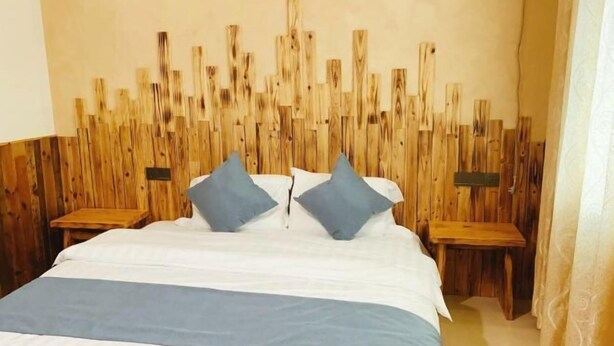 A bedroom with a wooden headboard, a bed with white bedding and two pillows, and two bedside tables. - Qingdeng Mountain House (Lin'an Baima cliff scenic spot store) (Hangzhou)