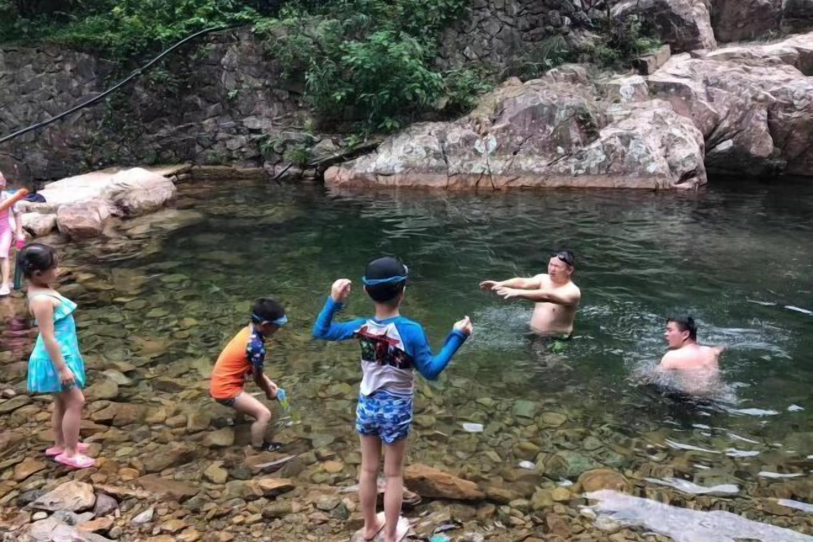 Un grupo de personas en un entorno acuático natural, rodeado de rocas y follaje.