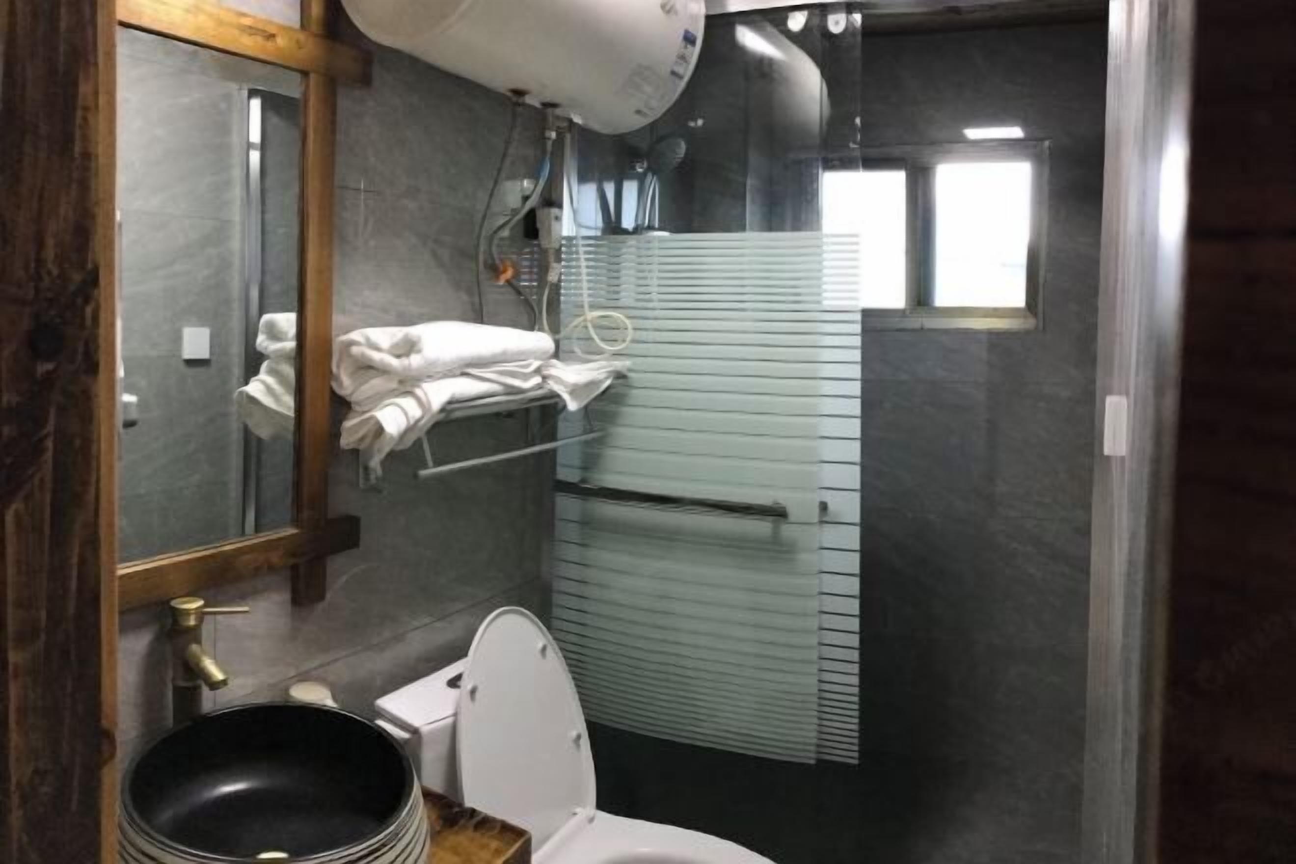 A bathroom with a white toilet, a black sink, a mirror, and a towel rack.