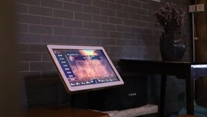 A tablet displaying a game interface, a brick wall, a vase with dried flowers, and a wooden table. - Qingdeng Mountain House (Lin'an Baima cliff scenic spot store) (Hangzhou)