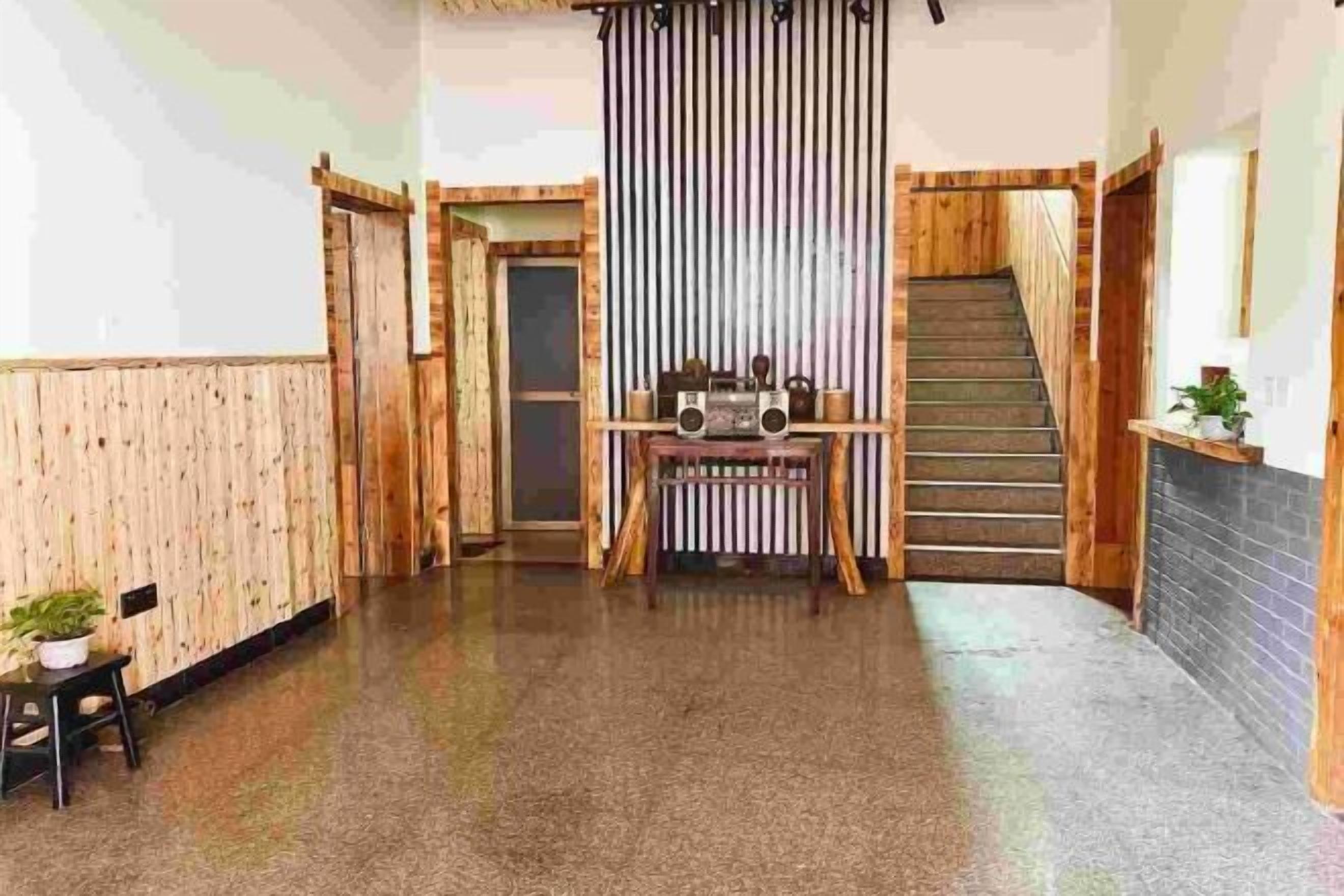 A hallway with wooden paneling, a staircase, and a table with a radio.
