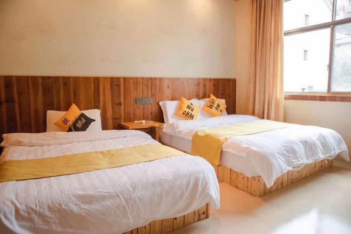 A hotel room with two beds, wooden headboard, and a window with curtains.