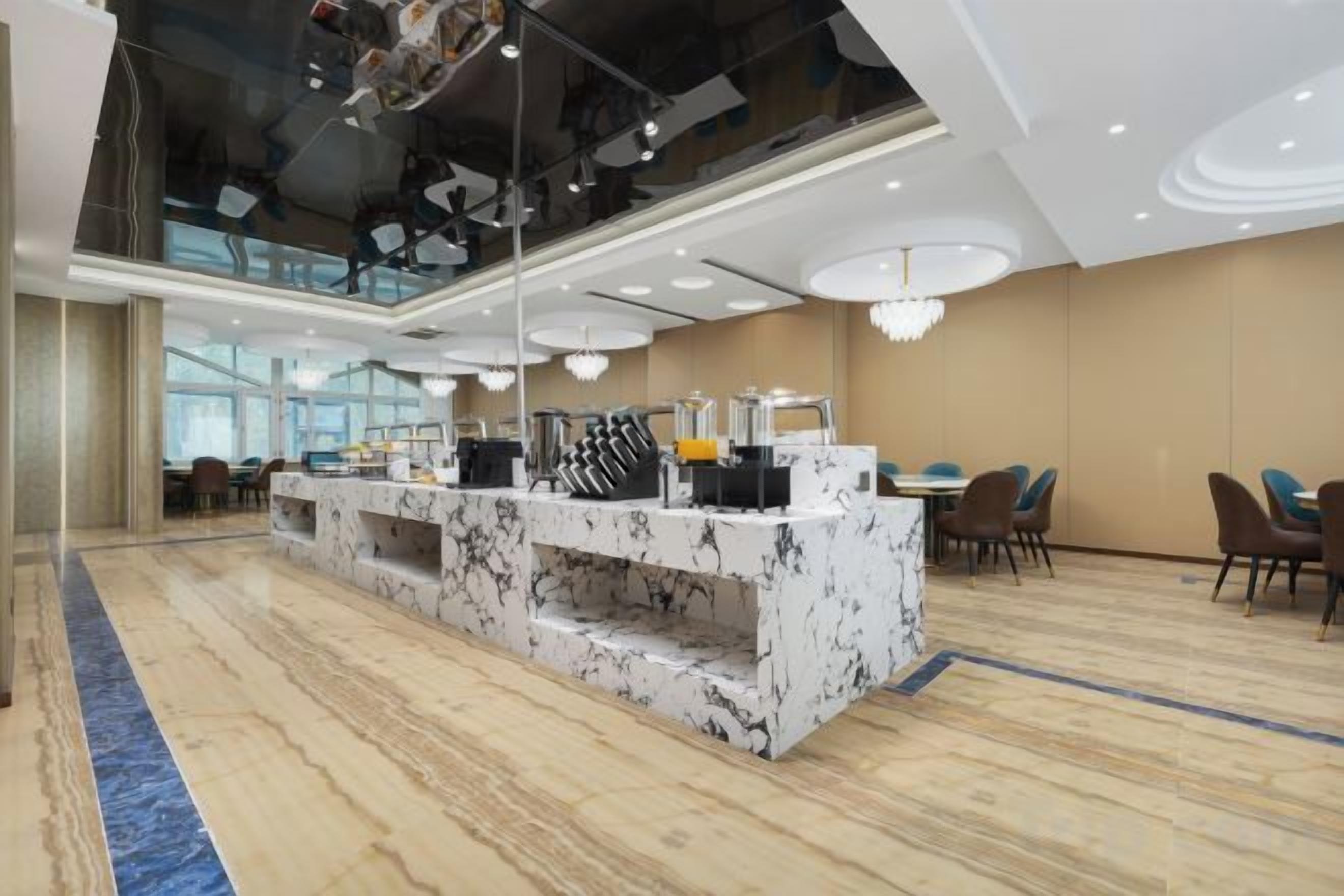 A modern hotel lobby with a marble reception desk, seating area, and large windows.