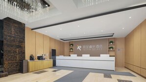 Ein moderner Hotel-Empfangsbereich mit Marmorboden, Holzvertäfelung, einer Rezeption und einem Chandelier.