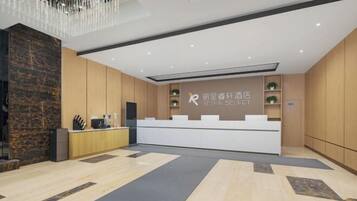 A modern hotel reception area with a marble floor, wooden paneling, a reception desk, and a chandelier.